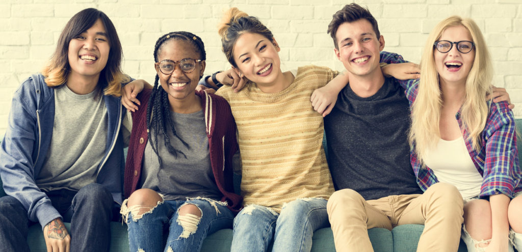 Five Teens sitting with arms around each other and smiling